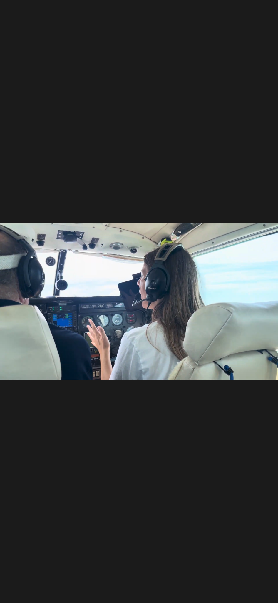 Elena wearing a headset at the controls inside a small aircraft cockpit